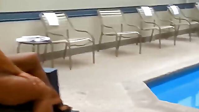 Athletic brunette in a blue bikini is posing next to the swimming pool and teasing a bit